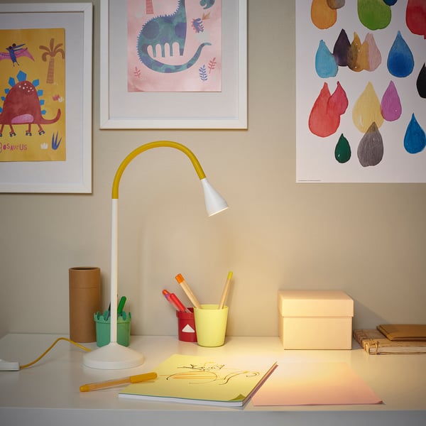 Desk lamp illuminates workspace with art supplies and minimalist decor.