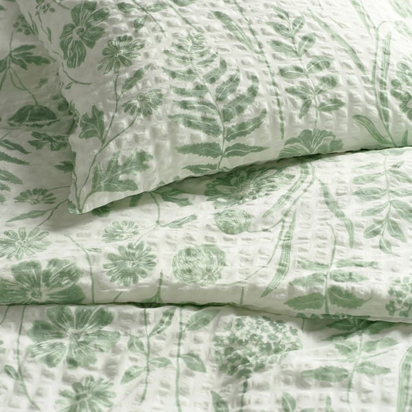 Soft, high-quality bedding with light green floral pattern on white; textured, breathable fabric.