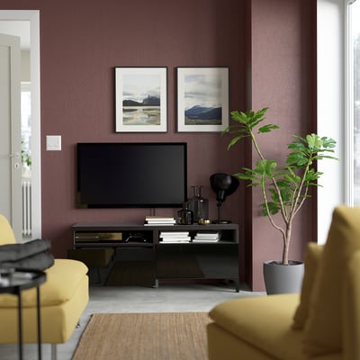 Modern living room with tv on black stand, yellow chair, and plant; purple walls and framed nature photos.