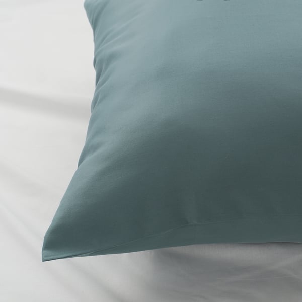 Close-up of stylish pillowcase with wave patterns. Calm blue-green, luxurious texture.