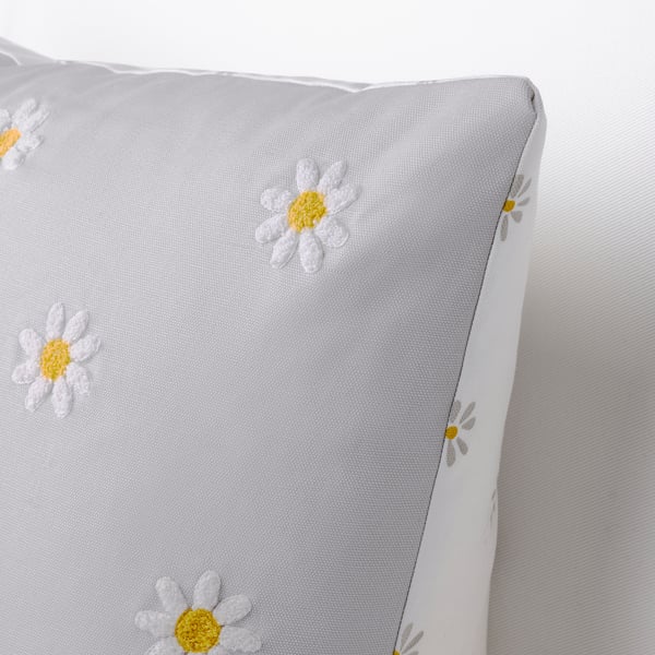 A plush cushion with white daisy tufts on a soft grey background.