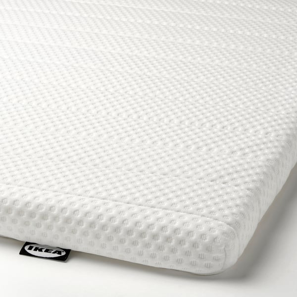 Close-up of a firm mattress pad with ikea tag. High resilience foam, clean white fabric, smooth texture.