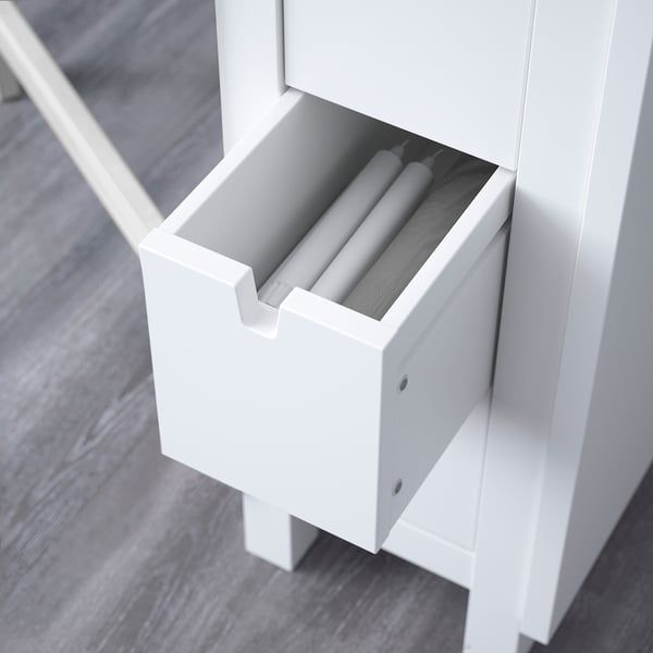 White cabinet with open drawer showing neatly rolled items.