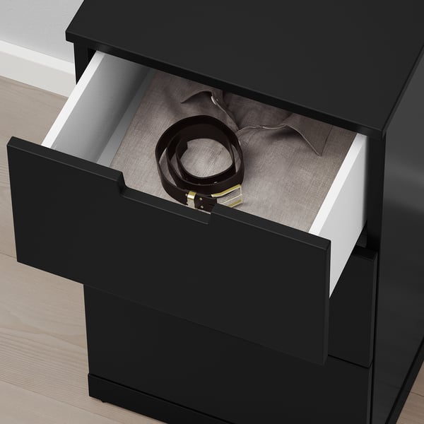 Black chest drawer open, revealing neatly coiled belts and folded ties inside. Drawer has smooth, slow-closing mechanism.