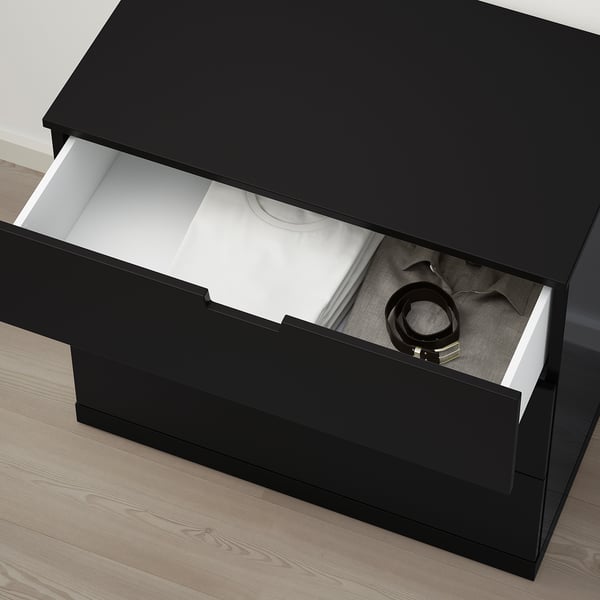 Black NORDLI dresser drawer open, showing interior with a belt and other items inside.