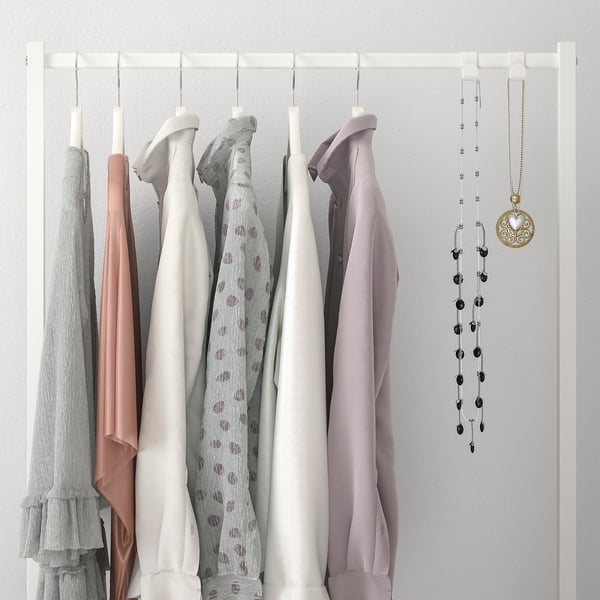 Closet rail displaying shirts in varied shades with hanging necklaces featuring moon charms.