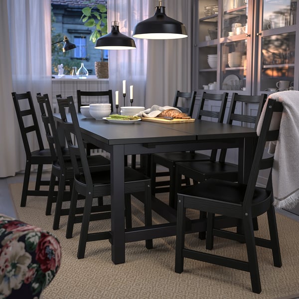 Modern black wooden dining table with six matching chairs, set for a meal under classic pendant lights.