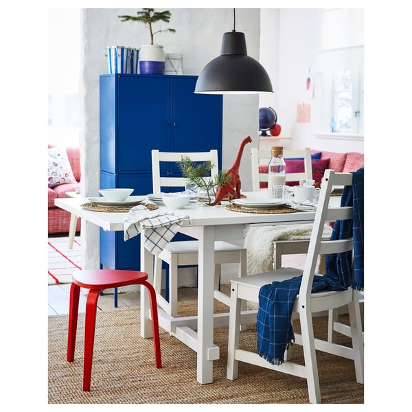 Dining room with extendable table, blue cabinet, white chairs, dinosaur toy, and black pendant lamp.