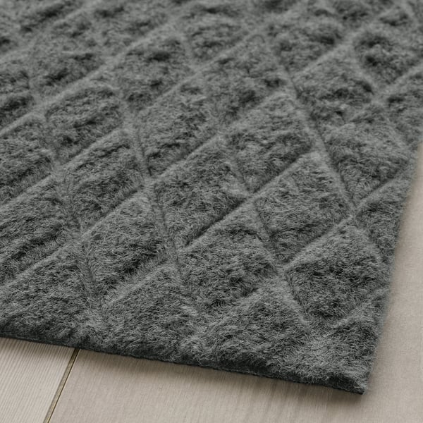 Grey textured doormat with diamond pattern on wooden floor.