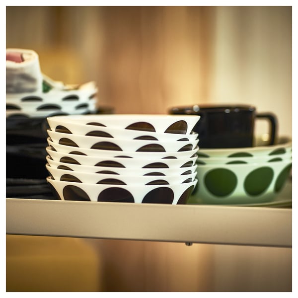 Stacked white OFTAST glass bowls with scalloped edges on a shelf, alongside green and grey bowls and a black mug.