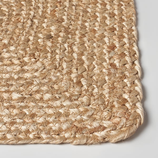 Close-up of intricately woven beige jute place mat, showcasing its tightly braided texture.