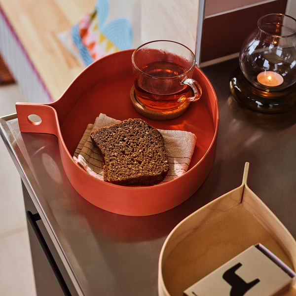 OMMJÄNGE red tray with bread, teacup, candle; birch veneer, sturdy, decorative teardrop shape.