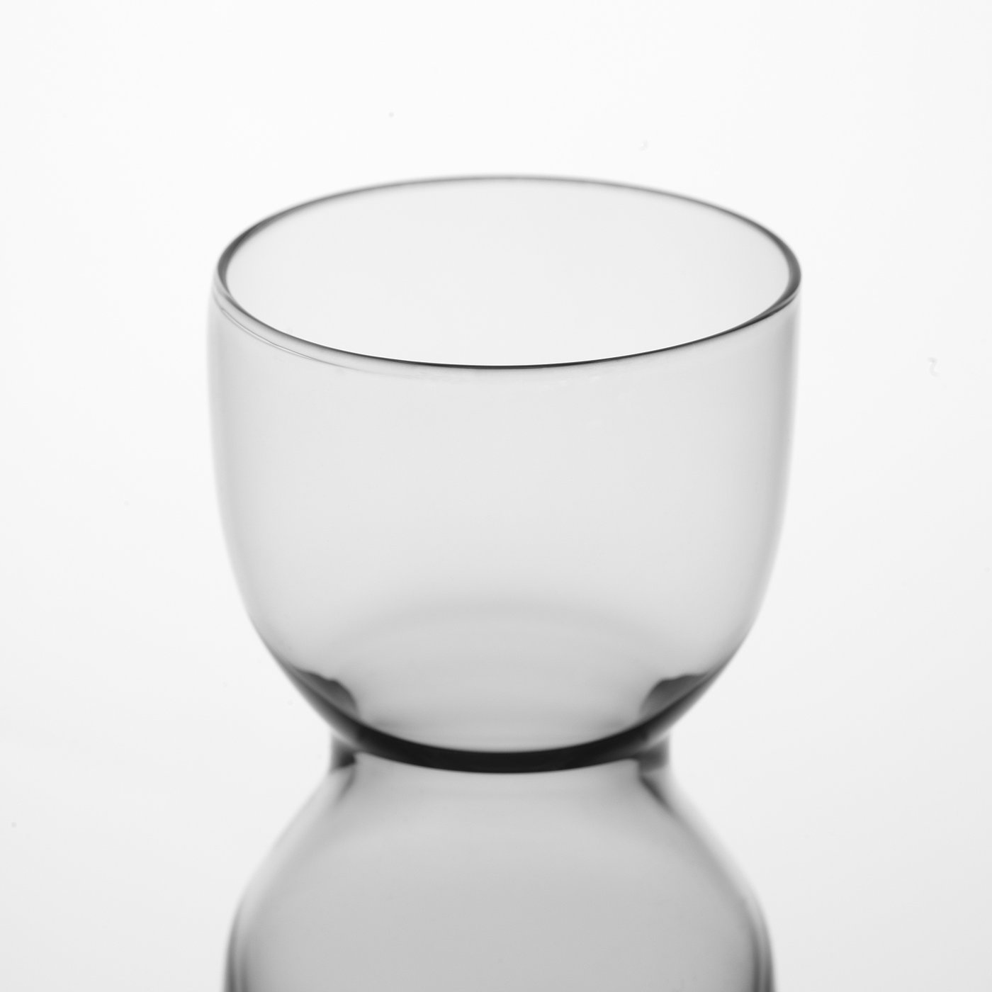 Clear glass vase shown, small and round with a smooth edge, reflecting light on its surface.