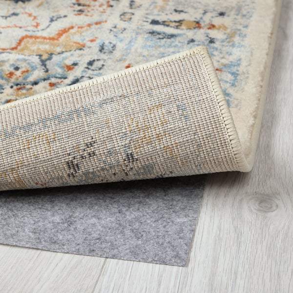 Rug with intricate, faded pattern showcasing quality craftsmanship; durable material and stain-resistant backing visible.