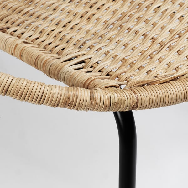 Close-up of woven rattan chair on black metal leg, showcasing intricate weave and sturdy construction.