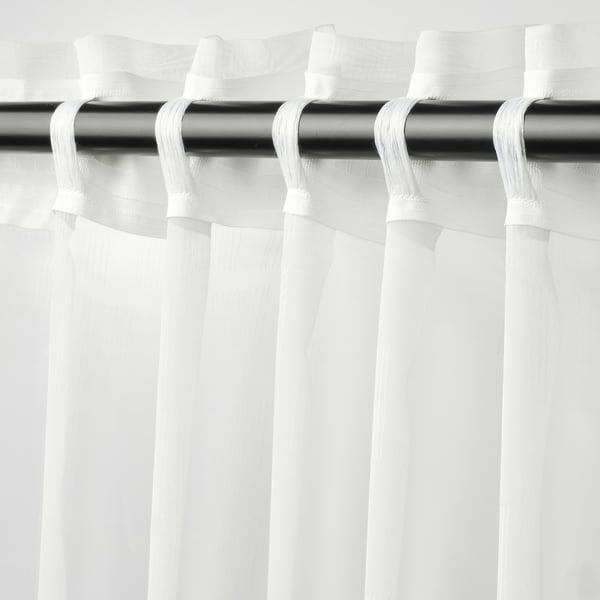 PALPLJUNGMAL curtains hang sheer, white with subtle texture, diffusing light, offering privacy while allowing outside connexion.