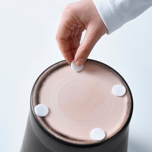 Hand placing a small white object onto a round pink item with three similar objects already attached.