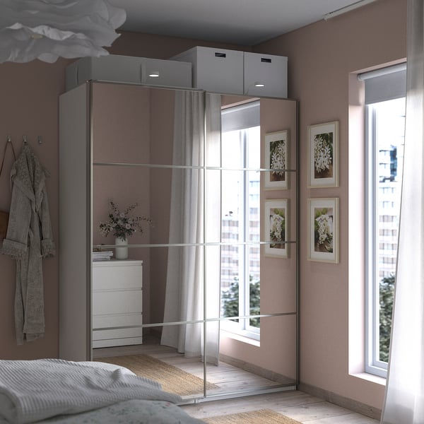 Modern bedroom with grey wardrobe, mirrored panels, soft lighting, and cosy bed.