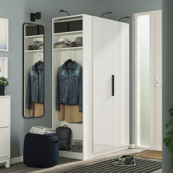 Modern white PAX wardrobe with mirror, jackets, hats, black stool, slim design.