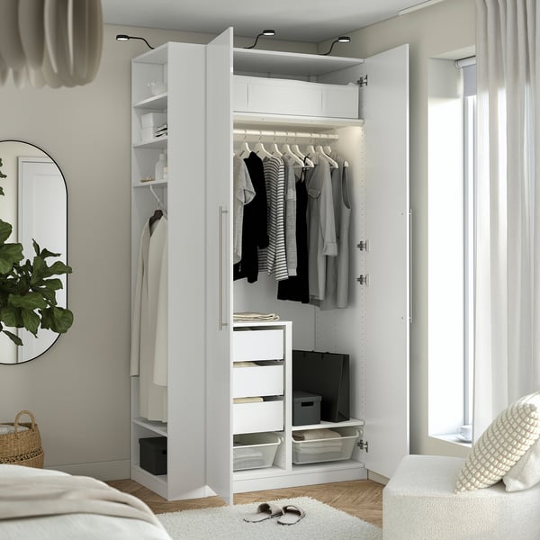 Organised white wardrobe with hanging clothes, drawers, and shelves. In-built lighting highlights stored items.