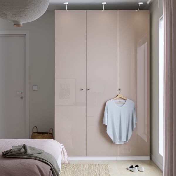 Modern bedroom with tall light pink PAX wardrobe, mesh basket holding blue shirt.