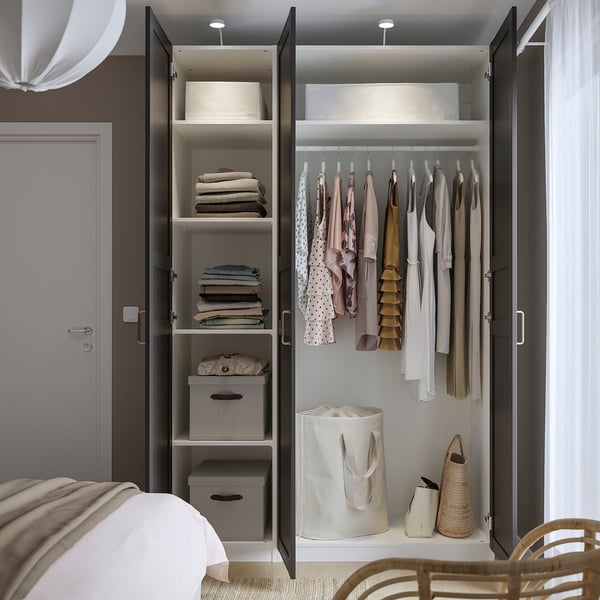 Open PAX wardrobe with folded clothes and hanging garments, well-lit and wall-fixed.
