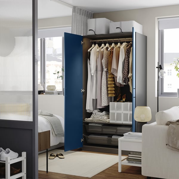Modern wardrobe with open door, hangers, clothes, shelves, and storage boxes in a minimalist room.