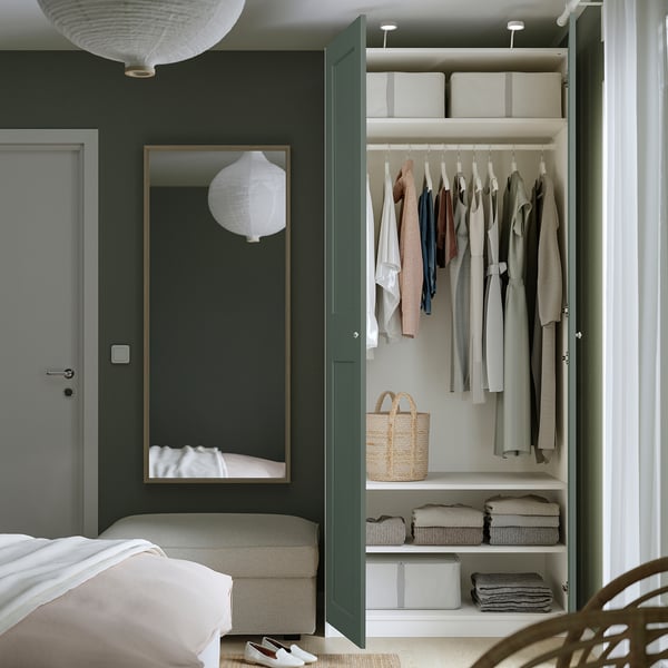 Bedroom with open wardrobe displaying clothes and storage, showing adjustable shelves and organised interior.