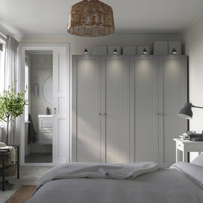 Modern bedroom with grey PAX wardrobe, bed, desk, and plant.