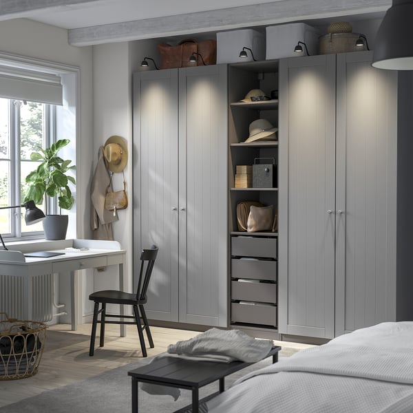 Large grey PAX wardrobe with open shelves and drawers, featuring a mesh basket, integrated lighting, and a wooden desk.