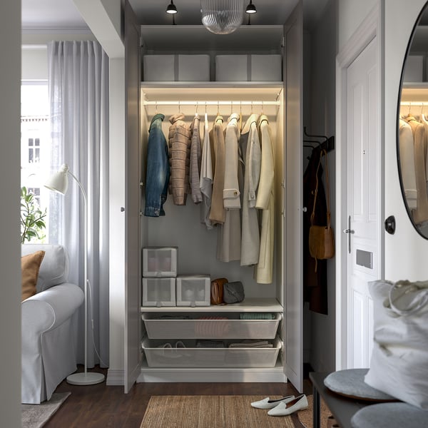 Open wardrobe displaying coats, shelves, and storage bins. Interior lighting illuminates neatly organised clothing and accessories.