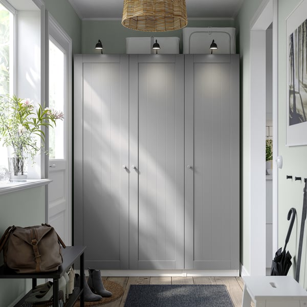 Large grey PAX wardrobes flank an entryway, towering over small furniture, with natural light pouring in.