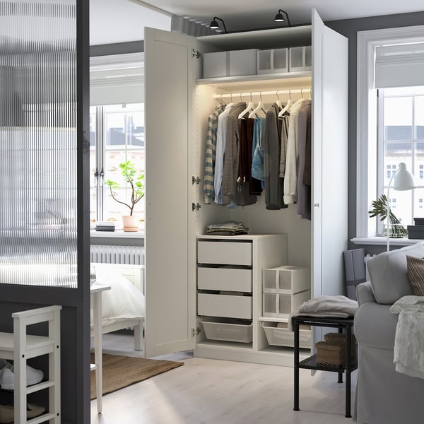 Modern white wardrobe, open showing clothes hangers, drawers, and integrated lighting. Soft-closing hinges evident.