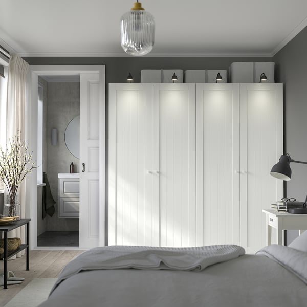 Minimalist bedroom: PAX wardrobe, integrated lighting, grey bed, desk, pendant light.