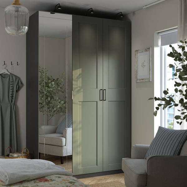 Modern bedroom with mirrored wardrobe, wood floor, grey decor, striped pillows, and plants.