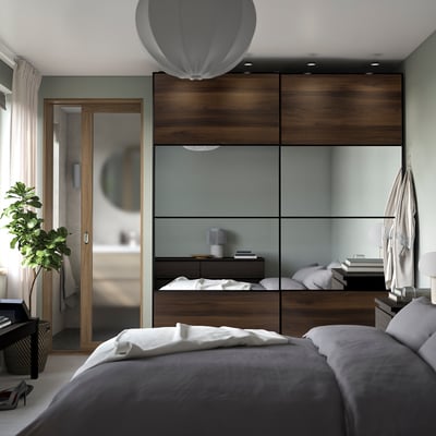 Modern bedroom with large mirrored PAX wardrobe, bed, pendant lamp and a plant.