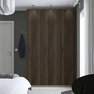Dark brown PAX wardrobe with mirrors, illuminated, near bed, blue jacket on hook.
