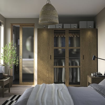 Modern bedroom with PAX wardrobe, bed, light, plant.