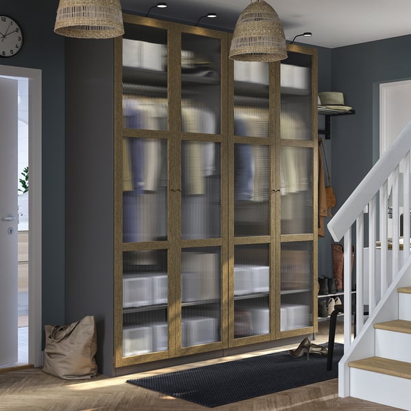 Modern cabinet set, PAX brand, tall & wide, light wood, glass doors. Black mat rug under. Near white stairs.