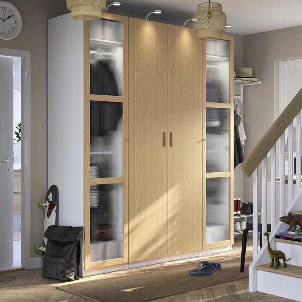 Wooden PAX wardrobe with glass panels, surrounded by decor and stairs.