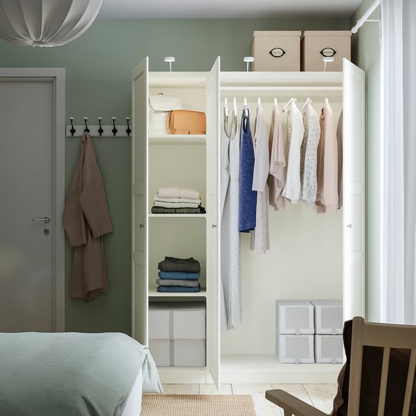 Closed PAX wardrobe with hangers, shelves, and cubes. Neutral clothes and accessories organised neatly inside.