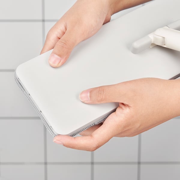 A person holding a white PEPPRIG microfiber mop cloth, designed for absorbent, quick-drying, and easy replacement.