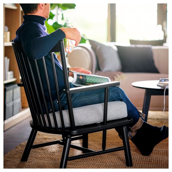 Person in black spindle chair using laptop. Near sofa, cushioned seat.