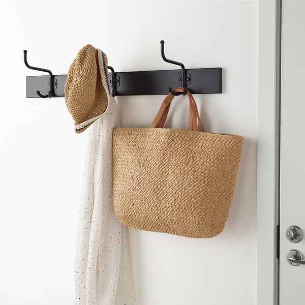 Wall-mounted rack with hooks, holding a woven bag and hat.