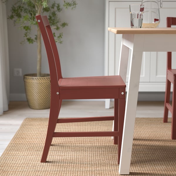 Red wooden chair with angled backrest and generous seat, positioned near a dining table.