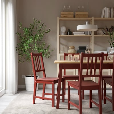 Modern dining room with red pine chair, olive tree, and bookshelf.