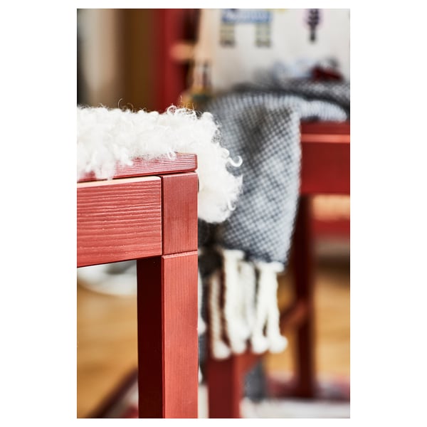 Red wooden table edge with white textured fabric, cosy home decor.