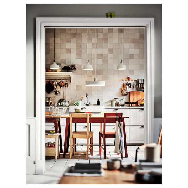 Cosy kitchen with red wooden table, warm floors, and modern lights.