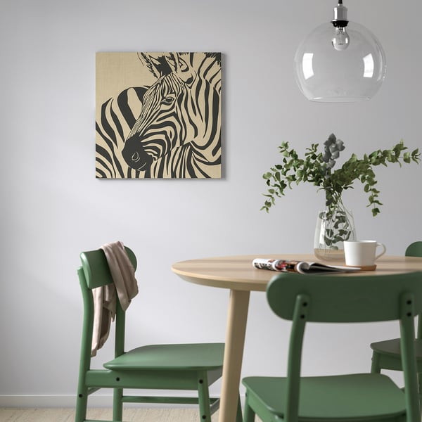 Zebra-themed wall art above small table with green chairs, vase, and pendant light.