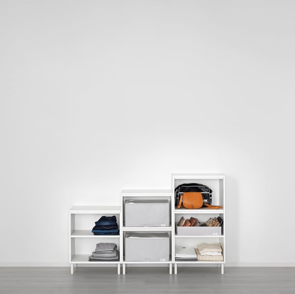 Modern white PLATSA storage units against a wall, neatly organising folded clothes, accessories, and bags.